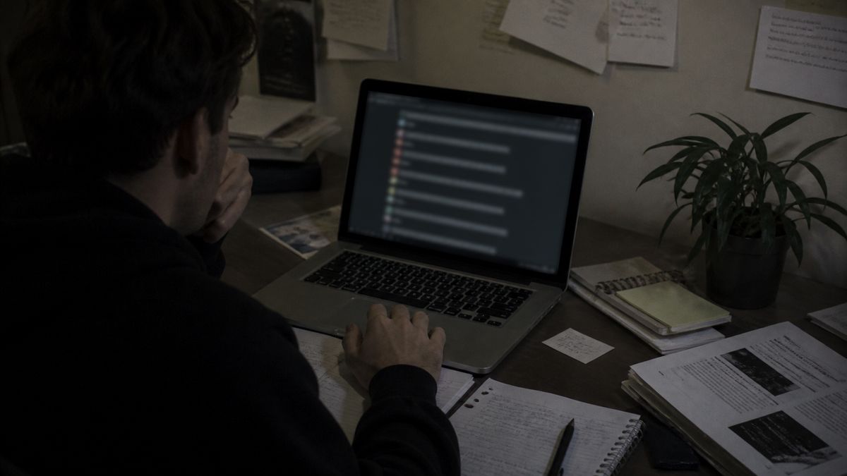 researcher at a desk with laptop and notes